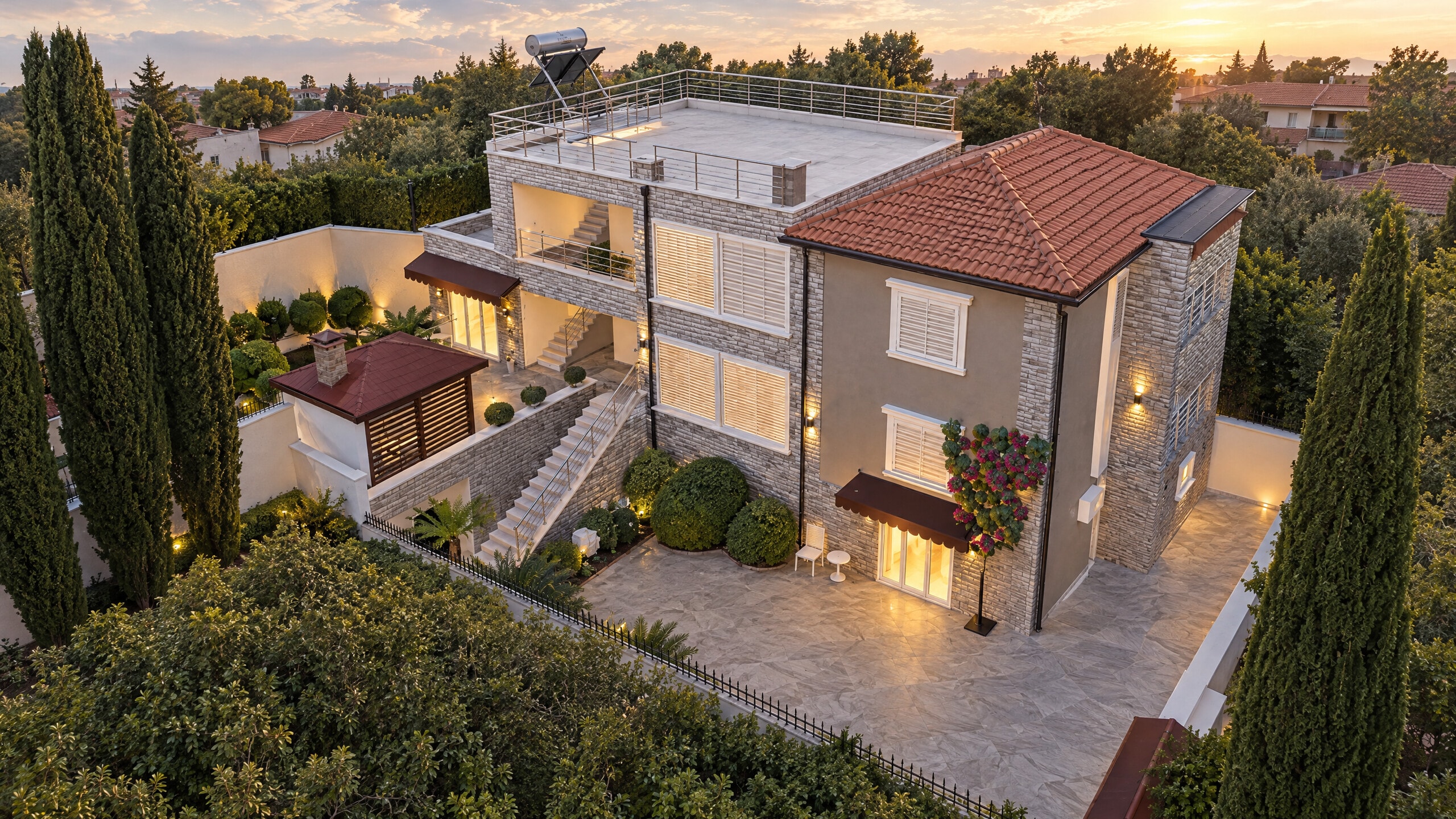 The villa at dusk: the stone house with its lit windows above the paved courtyard
